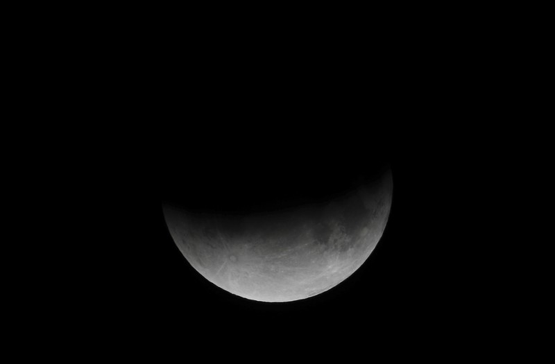 I this Tuesday, July 16, 2019 photo, men stand below street lights as the moon rises during a partial lunar eclipse in Buenos Aires, Argentina. (AP Photo/Natacha Pisarenko)
