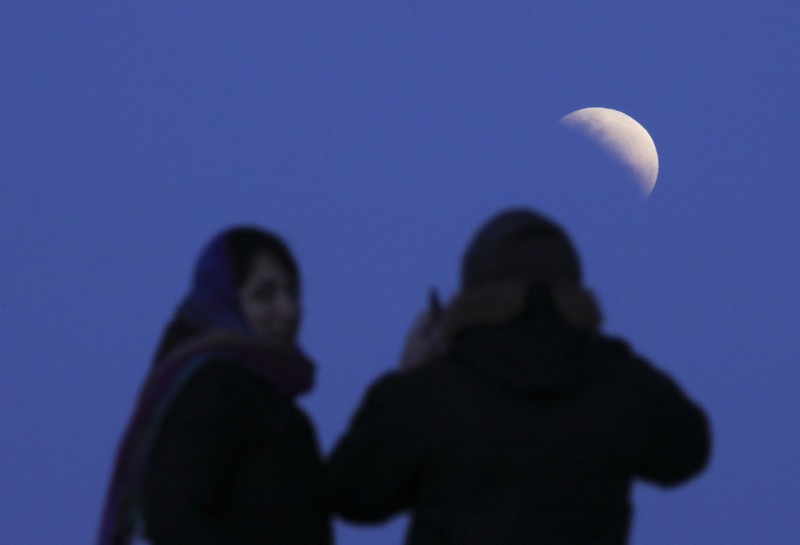 I this Tuesday, July 16, 2019 photo, men stand below street lights as the moon rises during a partial lunar eclipse in Buenos Aires, Argentina. (AP Photo/Natacha Pisarenko)