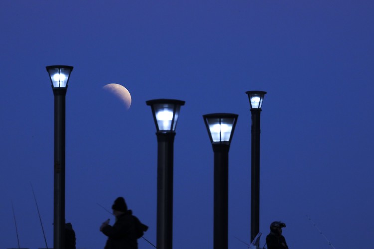 The Week That Was in Latin America Photo Gallery I this Tuesday, July 16, 2019 photo, men stand below street lights as the moon rises during a partial lunar eclipse in Buenos Aires, Argentina. (AP Photo/Natacha Pisarenko)