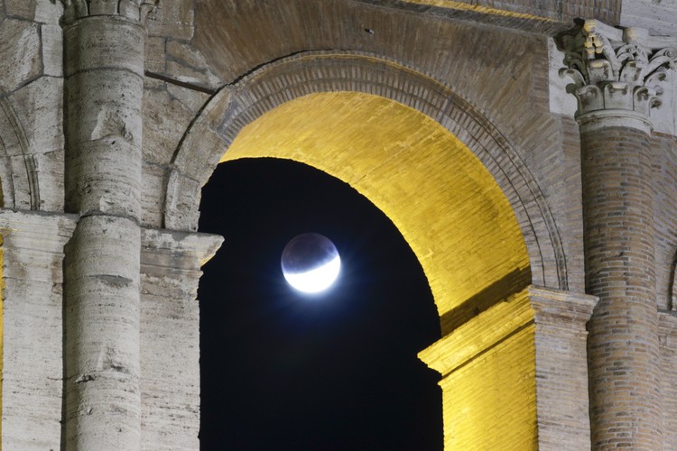 I this Tuesday, July 16, 2019 photo, men stand below street lights as the moon rises during a partial lunar eclipse in Buenos Aires, Argentina. (AP Photo/Natacha Pisarenko)