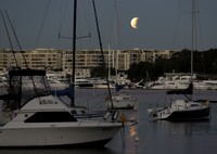 I this Tuesday, July 16, 2019 photo, men stand below street lights as the moon rises during a partial lunar eclipse in Buenos Aires, Argentina. (AP Photo/Natacha Pisarenko)
