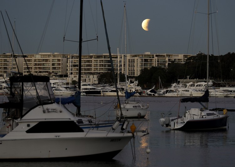 I this Tuesday, July 16, 2019 photo, men stand below street lights as the moon rises during a partial lunar eclipse in Buenos Aires, Argentina. (AP Photo/Natacha Pisarenko)