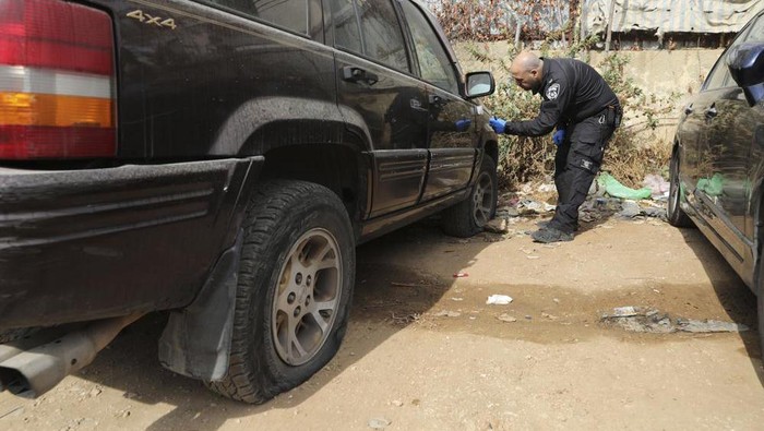 An Israeli police officer collects evidence from a vandalized vehicle in the Sheikh Jarrah neighborhood of east Jerusalem, Friday, Nov. 19, 2021. Residents from the tense Jerusalem neighborhood say the car tires of 11 Palestinian-owned vehicles were slashed by Israeli settlers. Palestinian families from the neighborhood are currently embroiled in a high-profile eviction case against Israeli settlers. (AP Photo/Mahmoud Illean)