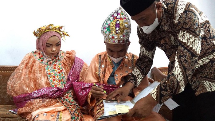 Salah seorang tahanan berinisial AL (tengah) menandatangani berkas pernikahan usai melaksanakan akad nikah di Lembaga Pemasyarakatan (Lapas) Klas IIA, Kota Gorontalo, Gorontalo, Sabtu (20/11/2021). AL yang masih berstatus terdakwa diberikan izin untuk melangsungkan pernikahan setelah mendapatkan penetapan dari pengadilan yang dilaksanakan oleh Kejaksaan serta difasilitasi oleh Lapas. ANTARA FOTO/Adiwinata Solihin/wsj.