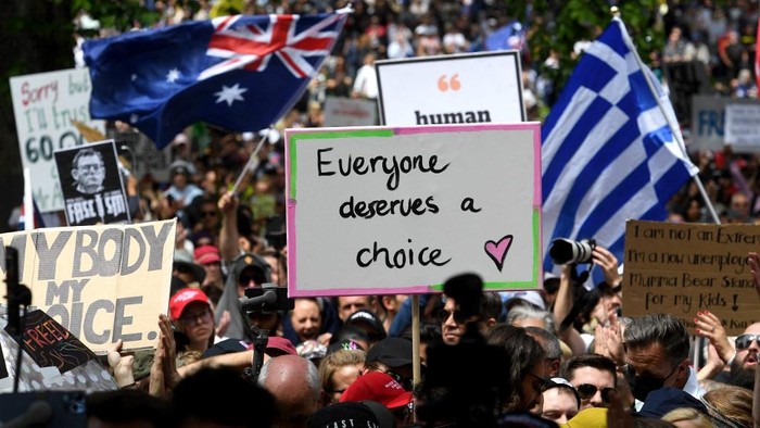 People hold up placards during a rally against Covid-19 lockdown and vaccination measures in Melbourne on November 20, 2021. (Photo by William WEST / AFP)