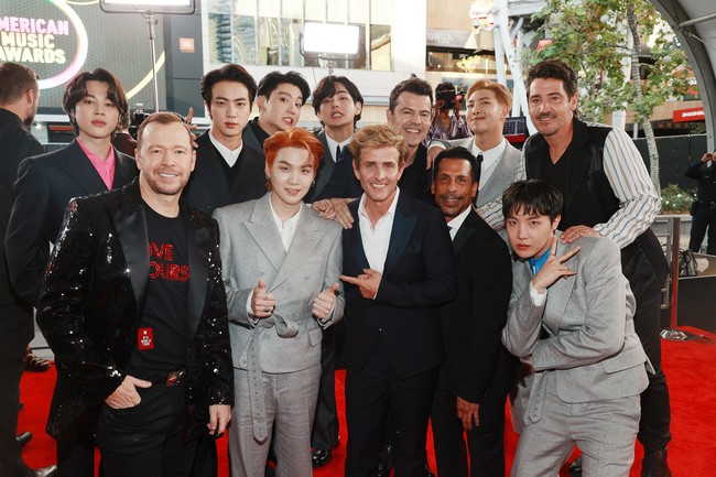 Para personel BTS berfoto bersama lima personel boyband New Kids on the Block sebelum memasuki venue acara AMAs 2021 yang diadakan di Microsoft Theather, Los Angeles, California. Foto: Getty Images for MRC/Matt Winkelmeyer