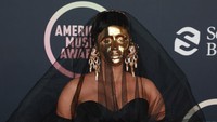 Penampilan Cardi B semakin mencolok dengan dress hitam panjang, tudung hitam transparan, dan perhiasan emas di jari-jari tangannya. (Foto: Getty Images for MRC/Matt Winkelmeyer) 