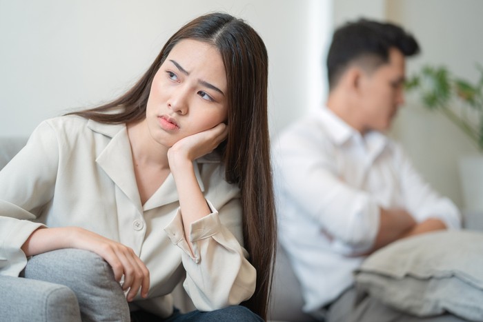 ilustrasi pasangan Young couple in quarrel at home.sadness young Asian woman sitting on sofa with boyfriends.relationship problems between couples and communication issues concept