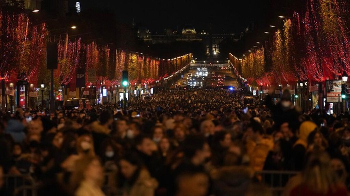 Spectators walk and take pictures after attending the Champs Elysee Avenue illumination ceremony for the Christmas season, in Paris, Sunday, Nov. 21, 2021. (AP Photo/Christophe Ena)