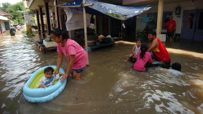 Balita Ini Bermain di Tengah Banjir Banjir akibat curah hujan yang tinggi merendam Kelurahan Pesurungan, Tegal, Jawa Tengah. Begini aktivitas warga di tengah banjir.