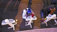 Orang-orang menulis pesan di salib sebelum menyalakan lilin di pusat kota Waukesha. AP/Jeffrey Phelps