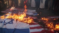 Pendukung Houthi membakar spanduk bergambar bendera Israel dan AS dalam unjukrasa di Ibu Kota Sanaa, Yaman, (22/11).