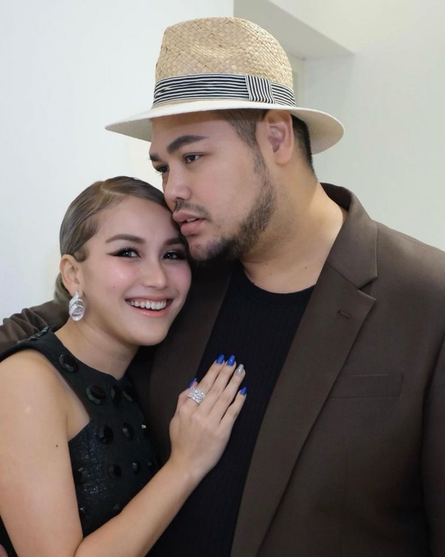 Dalam foto ini Ayu dan Ivan Gunawan tampak kompak dengan busana senada. Ayu tampak cantik dengan gaun berwarna hitam, sedangan Ivan mengenakan jas berwarna coklat gelap dengan dalaman berwarna hitam. Foto: Instagram/@ayutingting92