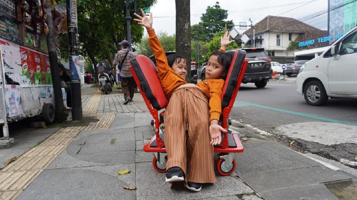 Ai Putri Dewi Ningsih (8) dan Ai Putri Anugrah (8) semringah ketika melihat kursi roda yang didesain khusus untuk mereka telah rampung dibuat. Bocah kembar siam asal Kecamatan Wanaraja, Kabupaten Garut itu akhirnya bisa kembali bergerak bebas.