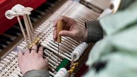 Karyawan menyetel piano yang baru diproduksi. Satu dari setiap tujuh piano di dunia dibuat di Yichang