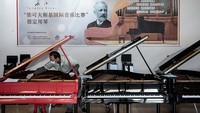 Seorang karyawan tengah menyetel piano yang baru diproduksi.