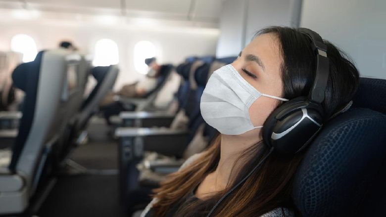 Portrait of a Latin American woman traveling by plane wearing a facemask and sleeping onboard