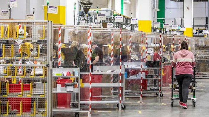 Pekerja mengepak barang saat memenuhi pesanan di gudang Amazon di Brieselang, Jerman, Minggu (22/11/2021).