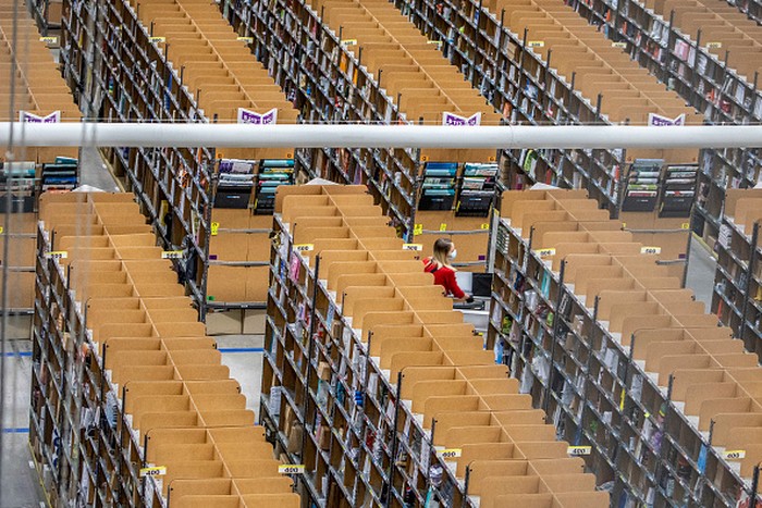 Pekerja mengepak barang saat memenuhi pesanan di gudang Amazon di Brieselang, Jerman, Minggu (22/11/2021).