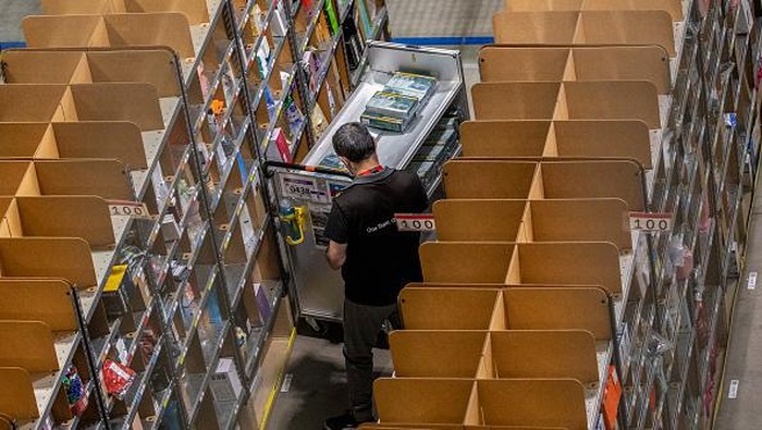 Pekerja mengepak barang saat memenuhi pesanan di gudang Amazon di Brieselang, Jerman, Minggu (22/11/2021).