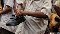 Seorang anak tampak mendapatkan sepatu berwarna hitam yang dibagikan oleh relawan CT Arsa Foundation dibantu oleh sejumlah guru di sekolah tersebut.