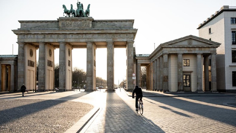 Lone biker riding past Berlins Brandenburg Gate as the city experiences its first day with movement restrictions introducing by the German government to mitigate the spread of COVID-19 Corona-virus