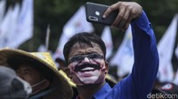 Salah seorang peserta aksi tampak melakukan swafoto saat ikut serta dalam aksi memantau jalannya putusan sidang MK terkait UU Cipta Kerja di kawasan Patung Kuda, Jakarta.