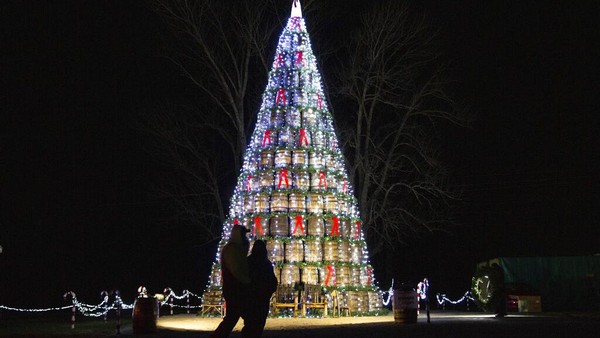 Dua orang warga melihat pohon Natal yang disusun dari ratusan gentong kayu di kawasan Kentucky, Amerika Serikat, Kamis (23/11/2021).