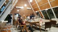 Jika memilih indoor berarti kamu bisa bersantai di dalam segitiga raksasa ini. Namun suasana outdoor juga asyik lho. Bangkunya dibangun berundak dengan meja kecil yang terlekat permanen. Warna abu membuatnya terasa lebih nyaman.