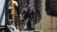Pekerja menggunakan mesin bobok dan palu untuk menghancurkan bangunan.