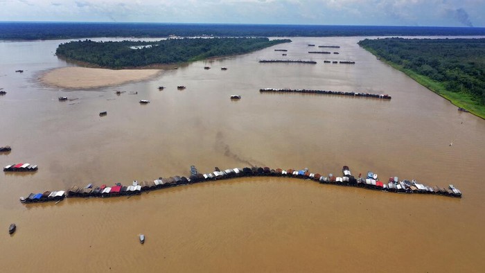 An illegal gold miner fixes a machine on a dredging barge on the Madeira river, a tributary of the Amazon river in Autazes, Amazonas state, Brazil, Thursday, Nov.25, 2021. Hundreds of mining barges have arrived during the past two weeks after rumors of gold spread, with environmentalists sounding the alarm about the unprecedented convergence of boats in the sensitive ecosystem. (AP Photo/Edmar Barros)