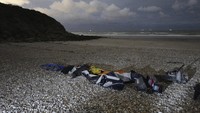 Jaket pelampung, kantong tidur, dan perahu kecil tiup yang rusak terlihat di pantai di Wimereux, Prancis utara, Jumat, (26/11/2021). AP/Rafael Yaghobzadeh