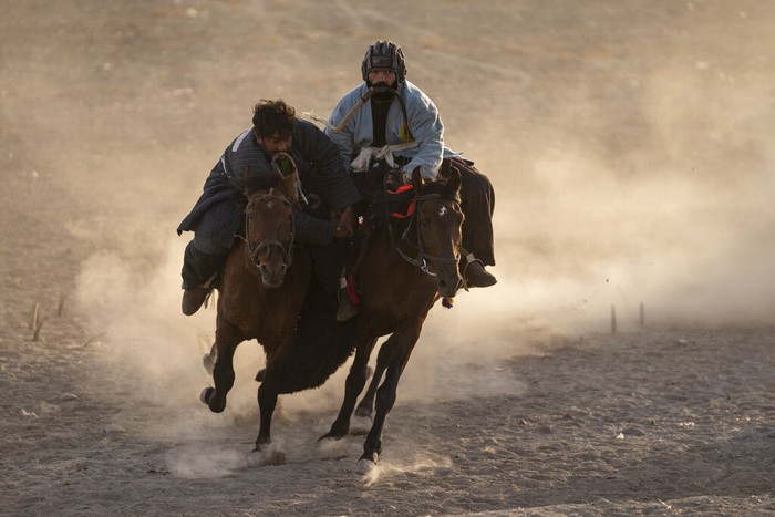 Para pemain Buzkashi bersaing memperebutkan kambing yang sudah disembelih dan berusaha membawa ke gawang di Herat, Afghanistan (26/11/2021).  Buzkashi merupakan olahraga budaya yang populer di Asia Tengah dan telah dimainkan sejak ratusan tahun lalu.