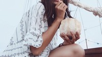 Wanita dengan nama asli Ni Luh Dharma Putri Marino tersebut juga dikenal hobi kulineran. Seperti pada foto yang ini, ia tengah menikmati air kelapa langsung dari batoknya. Foto: Instagram @putrimarino