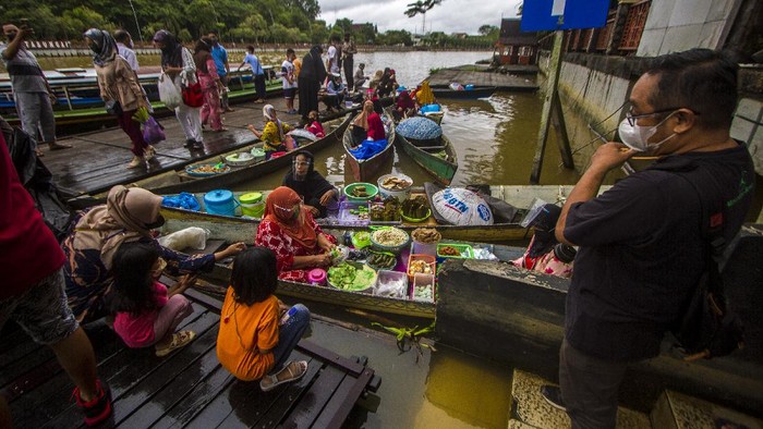 Pedagang melayani pembeli di wisata Pasar Terapung Siring Sungai Martapura di Banjarmasin, Kalimantan Selatan, Minggu (28/11/2021). Pemerintah Kota Banjarmasin kembali membuka salah satu obyek wisata andalan yaitu pasar terapung seiring status Pemberlakuan Pembatasan Kegiatan Masyarakat (PPKM) level 2 dengan pengawasan protokol kesehatan ketat serta pengunjung yang ingin masuk harus mengakses aplikasi PeduliLindungi. ANTARA FOTO/Bayu Pratama S/nym.