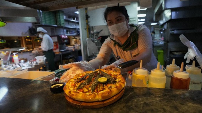Resto di Thailand Sajikan Pizza Toping Ganja A staff member shows a pizza topped with a cannabis leaf at a restaurant in Bangkok, Thailand on Nov. 24, 2021. The Pizza Company, a Thai major fast food chain, has been promoting its