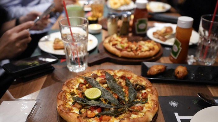 A staff member shows a pizza topped with a cannabis leaf at a restaurant in Bangkok, Thailand on Nov. 24, 2021. The Pizza Company, a Thai major fast food chain, has been promoting its 