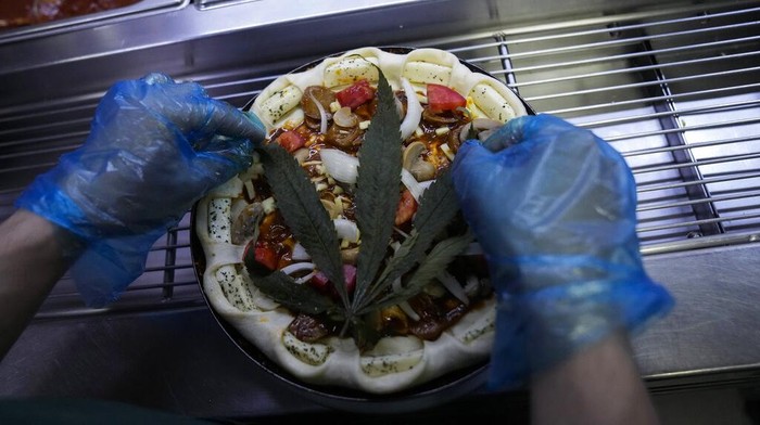 Resto di Thailand Sajikan Pizza Toping Ganja A staff member shows a pizza topped with a cannabis leaf at a restaurant in Bangkok, Thailand on Nov. 24, 2021. The Pizza Company, a Thai major fast food chain, has been promoting its