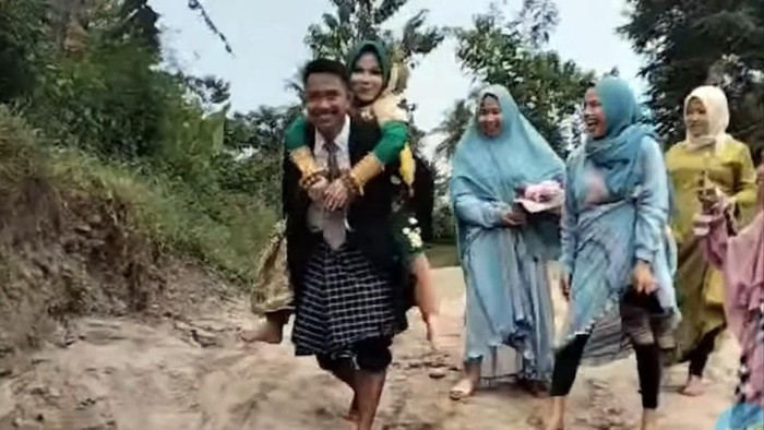 Seorang pengantin pria di Kabupaten Polewali Mandar, Sulawesi Barat, terpaksa menggendong istrinya menyeberangi sungai, karena ketiadaan jembatan.