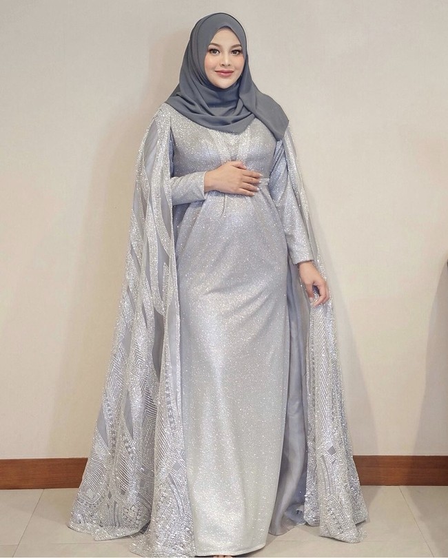 Aurel Hermansyah tampil anggun dan elegan dalam balutan gaun yang membuat baby bump-nya tampak menonjol. Aurel mengenakan dress glitter silver potongan cape pada lengannya, dipadu dengan hijab segi empat warna abu tua. Foto: Dok. Instagram @aurelie.hermansyah.