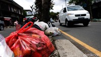 Sampah-sampah yang dimasukkan ke dalam kantong plastik dibuang  oleh warga ke median jalan.