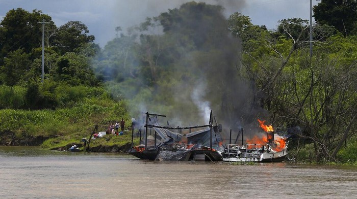 Petugas Institut Lingkungan dan Sumber Daya Alam Terbarukan Brasil, IBAMA, membakar sejumlah kapal tongkang milik penambang emas ilegal di sungai Madeira, anak sungai Amazon di Borba, negara bagian Amazonas, Brasil, Minggu, 28 November 2021. (AP Photo/Edmar Barros)