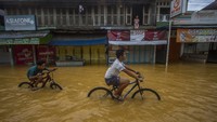 Dua orang warga bersepeda di tengah banjir yang merendam kawasan Barabai, Kabupaten Hulu Sungai Tengah, Kalimantan Selatan, Senin (29/11/2021).