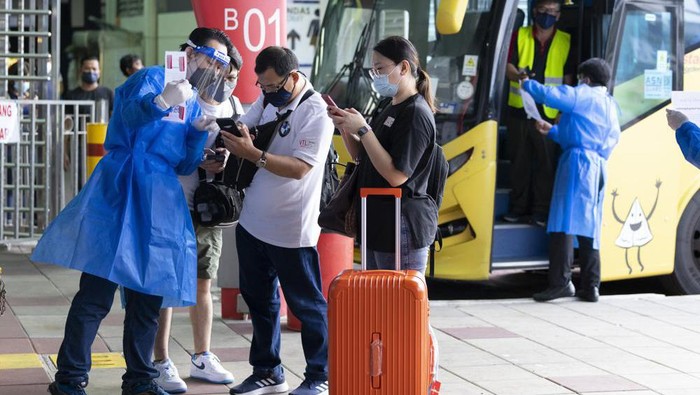 Passengers arrive from Singapore at Larkin bus station in Johor Bahru, Malaysia, Monday, Nov. 29, 2021. Malaysia and Singapore reopened their borders Monday, Nov. 29 for fully vaccinated citizens and some others, after nearly two years of closure due to the pandemic that had stranded many Malaysians working in the neighboring city-state away from their families. (AP Photo/Vincent Thian)