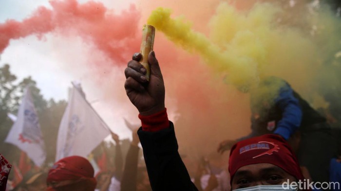 Saat berdemo di depan Balai Kota DKI Jakarta, massa buruh dari Konfederasi Serikat Pekerja Indonesia (KSPI) menyalakan flare berwarna-warni. Begini potretnya.