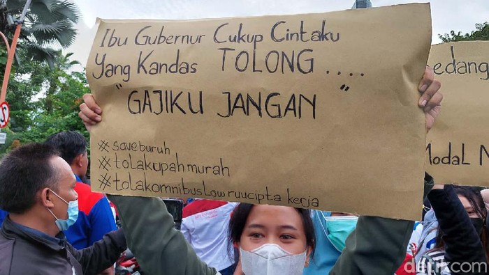 Massa buruh yang berdemo di Gedung Negara Grahadi, Surabaya, membawa bermacam spanduk. Di antaranya spanduk-spanduk lucu ini.