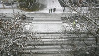 Orang-orang menunggu untuk melintasi zona pejalan kaki saat salju turun menutupi kota, di Pamplona, Spanyol utara. Pamplona berjarak 317 km sebelah utara Ibu Kota Madrid.