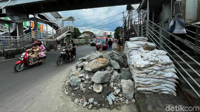 Tumpukan material batu dan karung pasir di Jalan Raya Bogor, Kramat Jati, Jakarta Timur, dikeluhkan warga. Pasalnya keberadaan material itu mempersempit jalan.