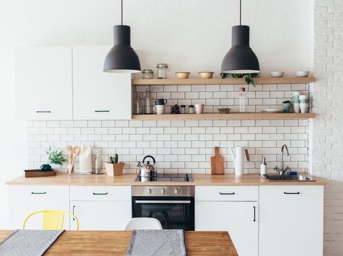 Modern new light interior of kitchen with white furniture and dining table