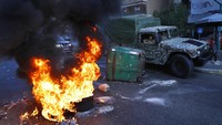 Tentara dengan kendaraan militer melewati ban yang dibakar oleh pengunjuk rasa selama protes terhadap kenaikan harga barang-barang konsumsi dan jatuhnya mata uang lokal.